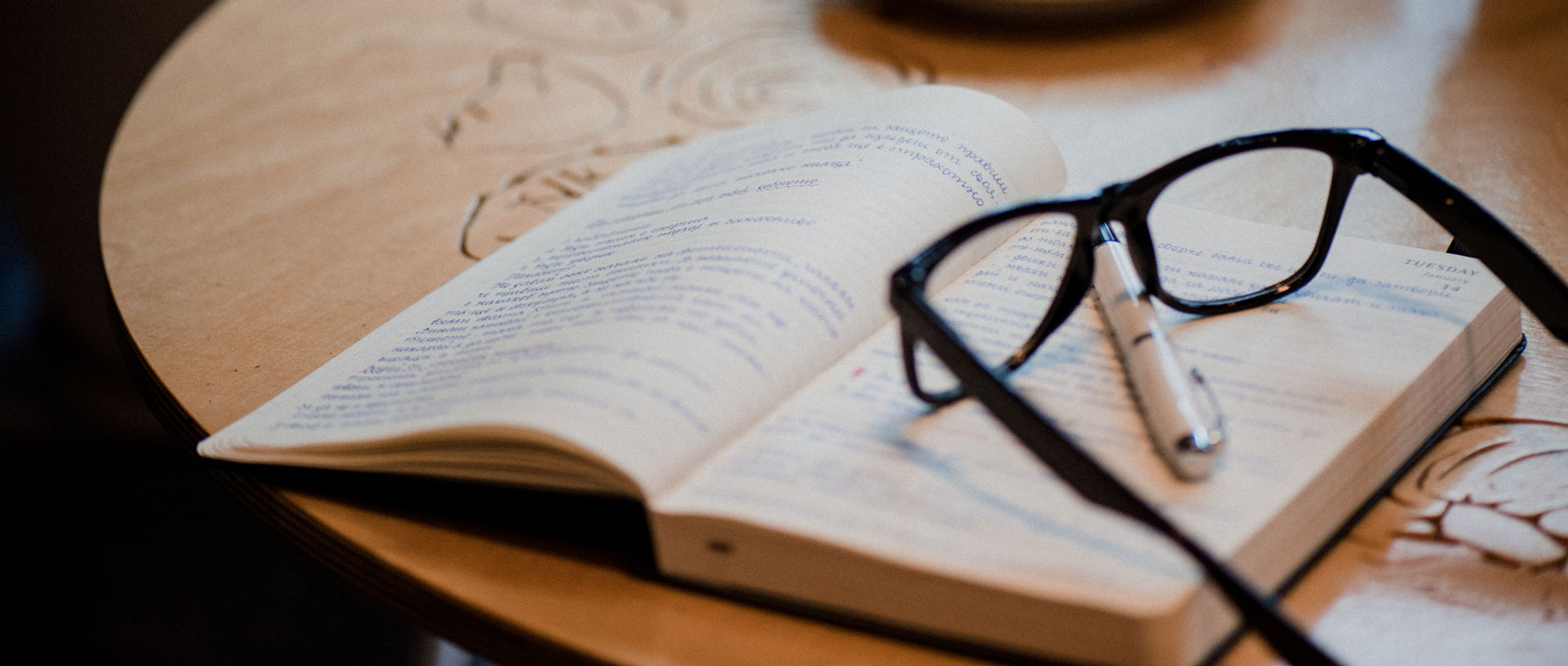 open book with hand written notes, spectacles and pen