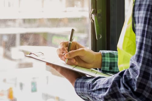 hands & clipboard with pen, wearing yellow vis-vest